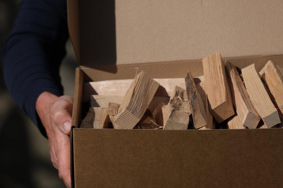 An open box of split ash kindling, held in both hands