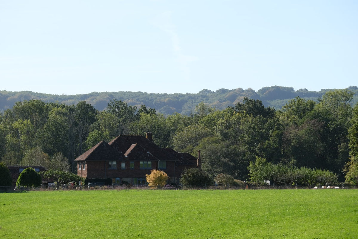 Lower Hawksfold seen across the field, with the wooded hills behind